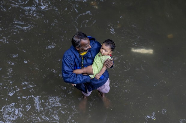 A man with his child at a flooded area after heavy rainfall owing to Cyclone Michaung, in Chennai. (PTI Photo)