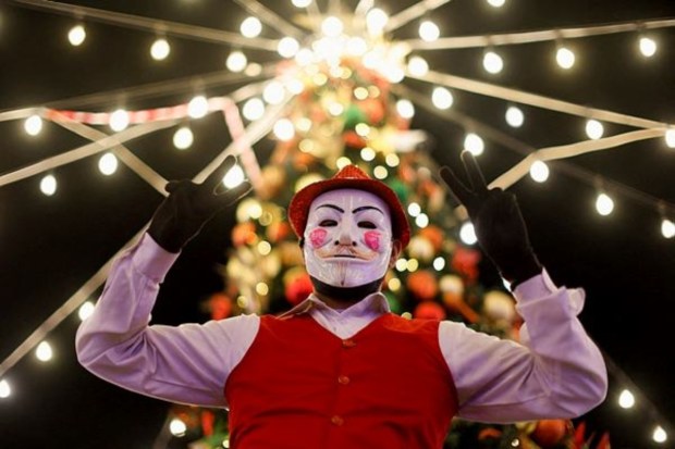 A joker poses in front of a Christmas tree at a season festival to celebrate Christmas Eve, in Al A'ali Mall, in Manama, Bahrain, on December 24. (Reuters)