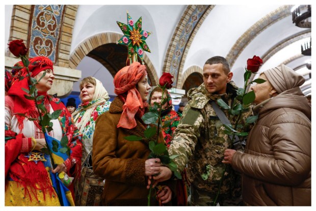 In Kyiv, Ukraine, a Ukrainian serviceman presents flowers to women dressed in traditional attire singing carols inside a metro station as Ukrainians celebrate their first Christmas according to the Western calendar amidst Russia's ongoing attack on Ukraine on December 25, 2023. (Image: Reuters)
