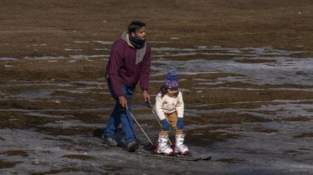 A Kashmiri ski instructor helps a young tourist to ski on a patch of snow in Gulmarg, northwest of Srinagar.