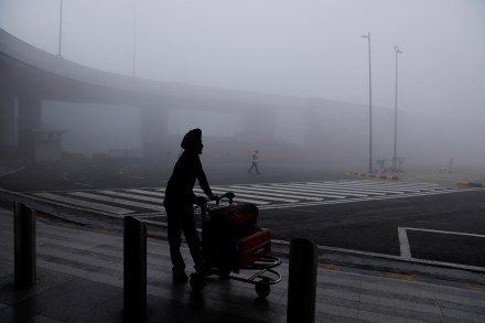 A man is seen with his luggage cart amidst heavy fog at the Indira Gandhi International Airport in New Delhi, India (Image/Reuters)