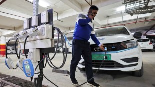 A man charges an electric vehicle (EV) at the charging hub of Indian ride-hailing BluSmart Electric Mobility in Gurugram (Image/Reuters)
