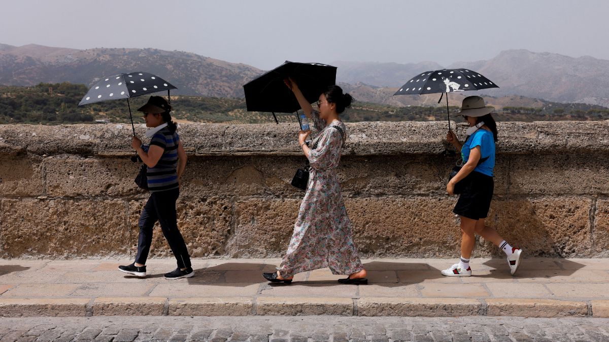 South Korean tourists shield themselves from the strong sun with umbrellas during Spain's third heatwave of the summer 2023