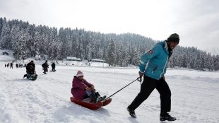 A man pulls a sledge carrying a tourist on a sunny day in Gulmarg (Image/Reuters)