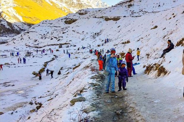 Tourists play with snow at the Koksar in Lahaul and Spiti district. (PTI Photo)