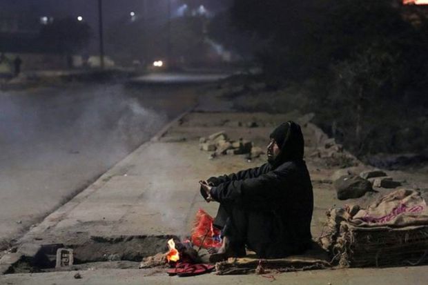 A man warms himself near a bonfire on a cold winter morning, in New Delhi, Saturday. (PTI Photo)