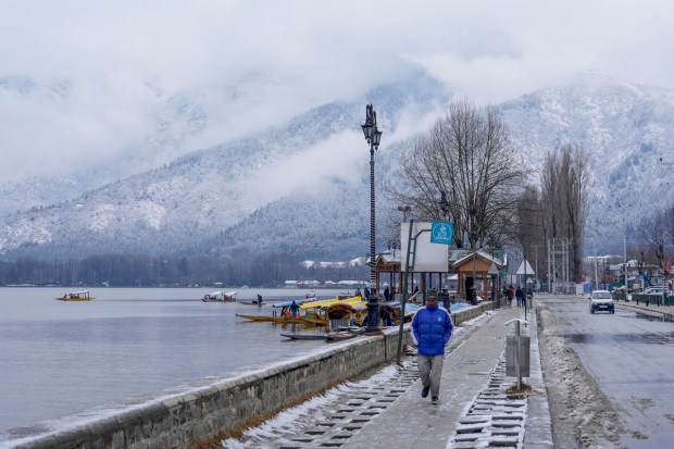 A pedestrian walk along Dal Lake after fresh snowfall in Srinagar (PTI Photo)