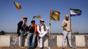Farmers hold flags at a protest site, during the march towards New Delhi