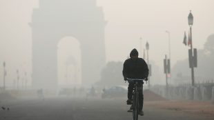 A man rides his bicycle in front of the India Gate shrouded in smog in New Delhi