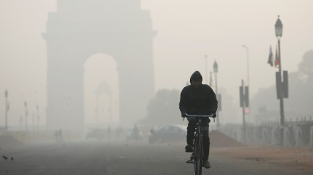 A man rides his bicycle in front of the India Gate shrouded in smog in New Delhi