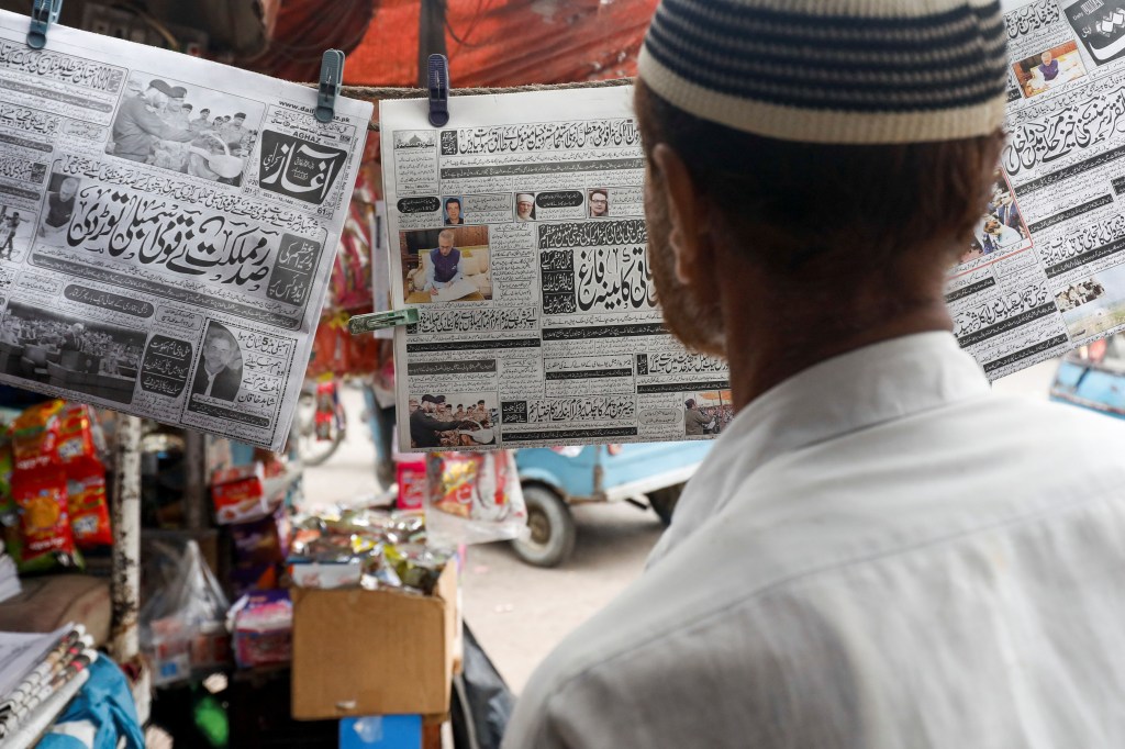 A man reads a newspaper at a stall in Karachi (Image/Reuters)