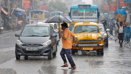A man carrying an umbrella runs as he crosses a busy road during heavy rains in Kolkata (Image/Reuters)