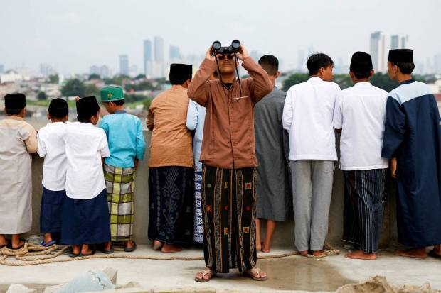 A Muslim man uses binoculars to look for the position of the moon to mark the first day of the holy fasting month of Ramadan, on the roof of Al-Musyari'in mosque in Jakarta, Indonesia. REUTERS