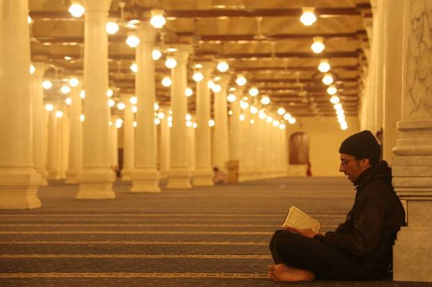 An Egyptian Muslim man reads the holy book of Quran after attending the evening prayers called 