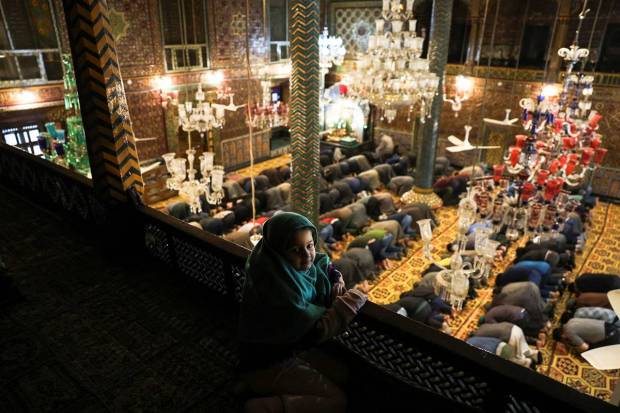 Kashmiri Muslim men offer afternoon prayers as a girl sits in a balcony inside the shrine of Sufi Saint Mir Syed Ali Hamadani on the second day of the Muslim holy fasting month of Ramadan in Srinagar. REUTERS