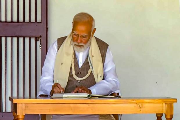 Prime Minister Narendra Modi writes in the visitor's book at Sabarmati Ashram ahead of the launch of master plan for Sabarmati Ashram project, in Gujarat's Ahmedabad. (PTI Photo)