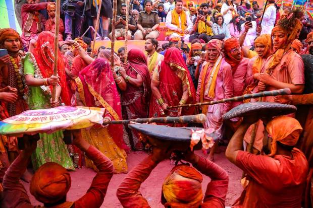 Women from Barsana beat men from Nandgaon during Latthamaar Holi celebration, in Barasana near Mathura. (PTI Photo)