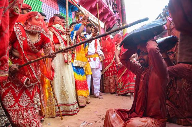 Women from Barsana beat men from Nandgaon during Latthamaar Holi celebration, in Barasana near Mathura. (PTI Photo)