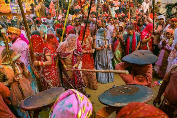 Women from Barsana beat men from Nandgaon during Latthamaar Holi celebration, in Barasana near Mathura. (PTI Photo)