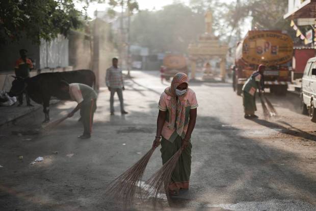 Workers from the Bruhat Bengaluru Mahanagara Palike (BBMP) clean the area outside a polling station a day ahead of the second phase of India's general election, in Bengaluru, Karnataka. REUTERS