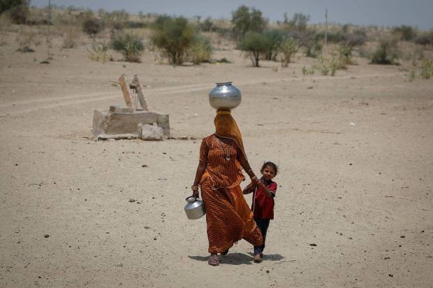 A woman walks back towards her home after filling water from a shallow well in a desert area on a hot summer day in Barmer, Rajasthan. REUTERS