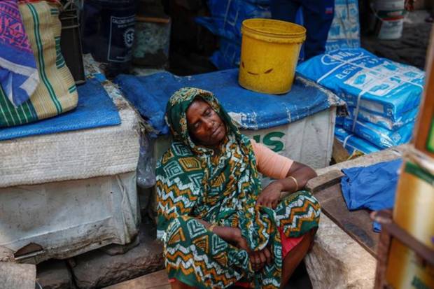 A woman rests by the sidewalk inside a market on a hot summer day in Kolkata. REUTERS