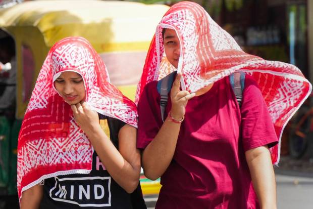 Women cover their head to shield themselves from the scorching sun on a hot summer day, in Lucknow. (PTI Photo)