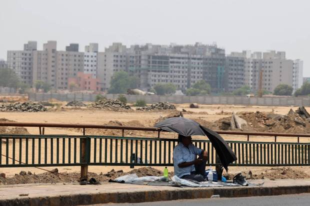 A stallholder sits in the shade, waiting for customers on a hot summer day in Ahmedabad. REUTERS