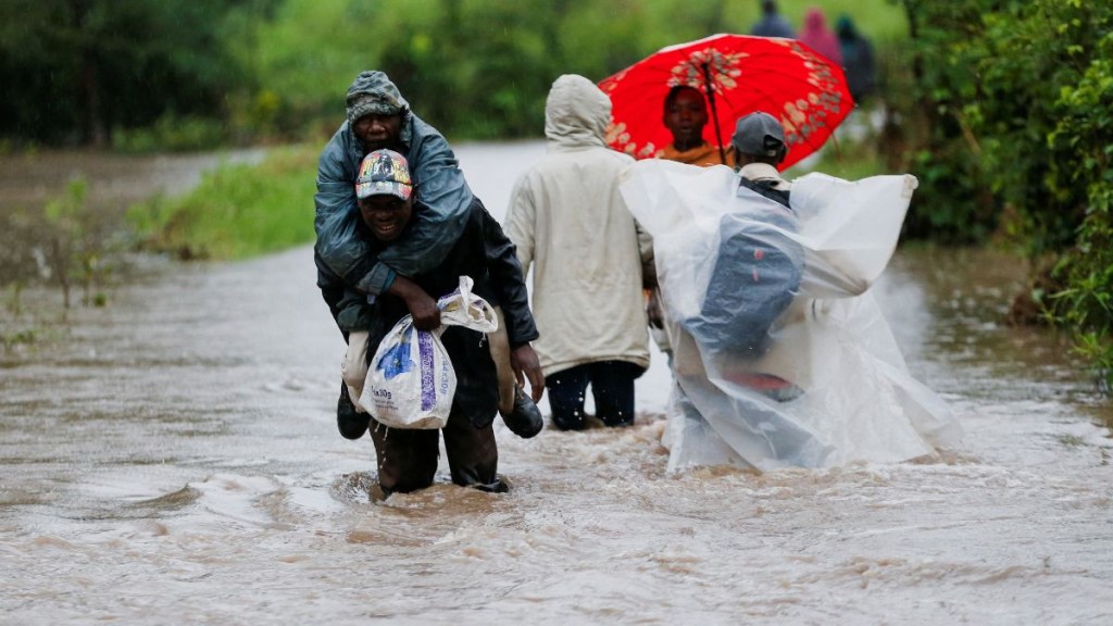Residents wade through flood waters after a seasonal river burst its banks following heavy rainfall