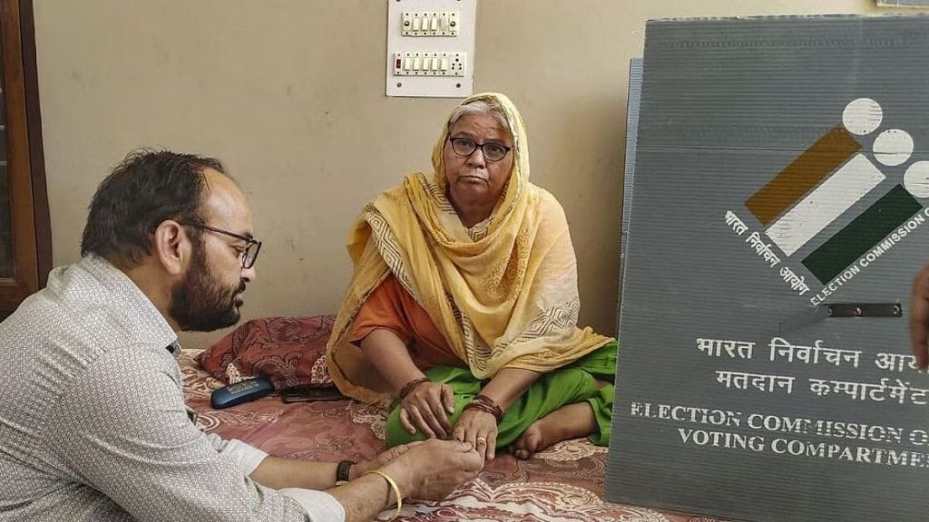 A polling official assists a senior citizen to cast her vote exercising the 'vote-from-home' facility for Lok Sabha elections, in Gurugram (Photo: PTI)
