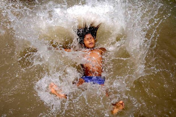 A child jumps into a water body for respite from the scorching sun, on a hot summer day, in Amritsar. (PTI Photo)