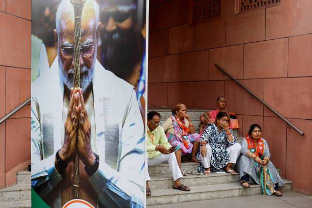People sit near an image of Indian Prime Minister Narendra Modi at the Bharatiya Janata Party (BJP) headquarters in New Delhi, India, June 4, 2024. REUTERS