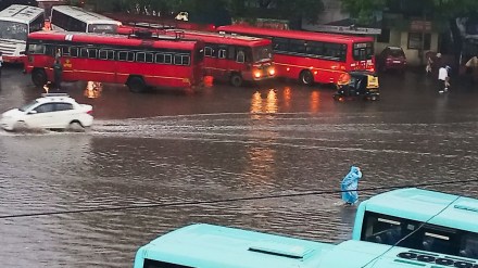 Commuters wade through a waterlogged road amid rains, in Pune