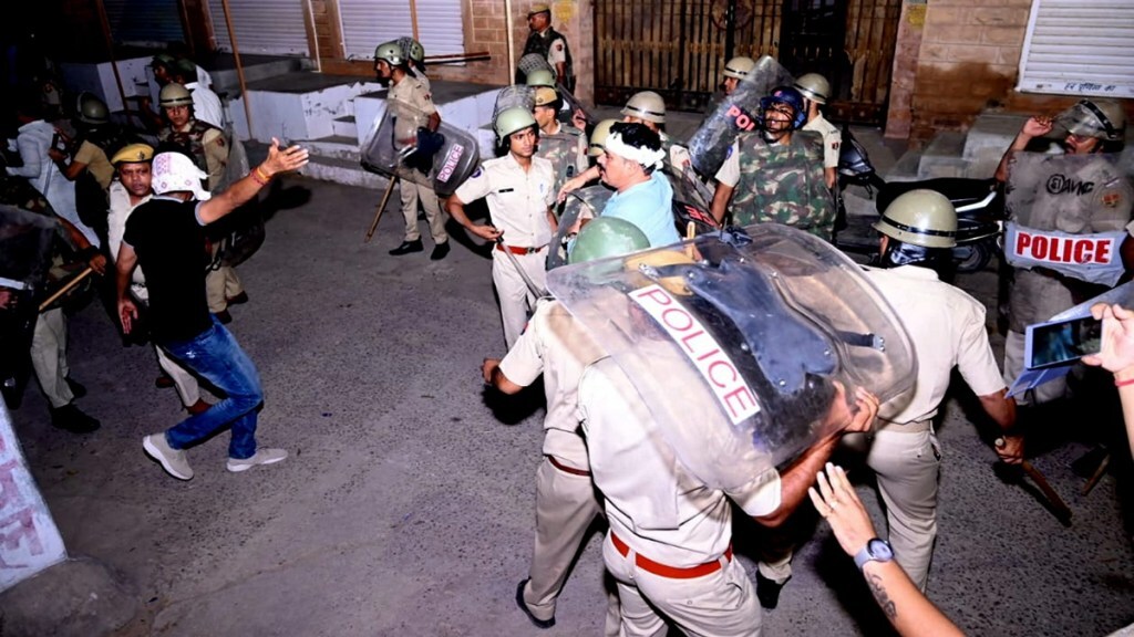 Police personnel detain a person after stone pelting took place during a clash between two groups, in Jodhpur, Friday night, June 21, 2024.