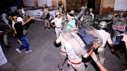 Police personnel detain a person after stone pelting took place during a clash between two groups, in Jodhpur, Friday night, June 21, 2024.