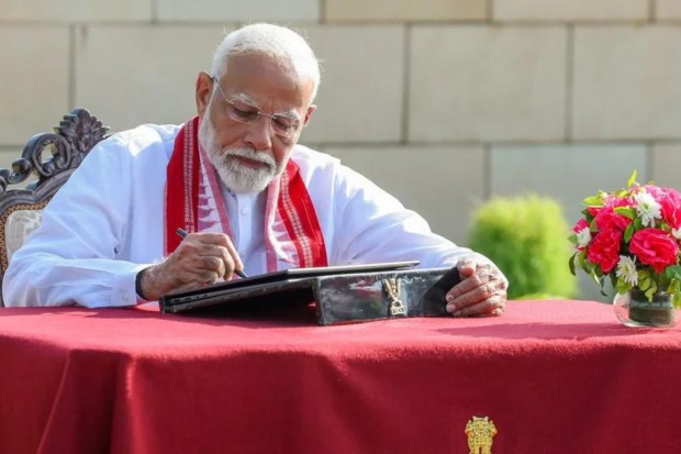 Narendra Modi scribbles down his thought in the Visitors' Book at the National War Memorial in New Delhi (Photo: BJP Media)