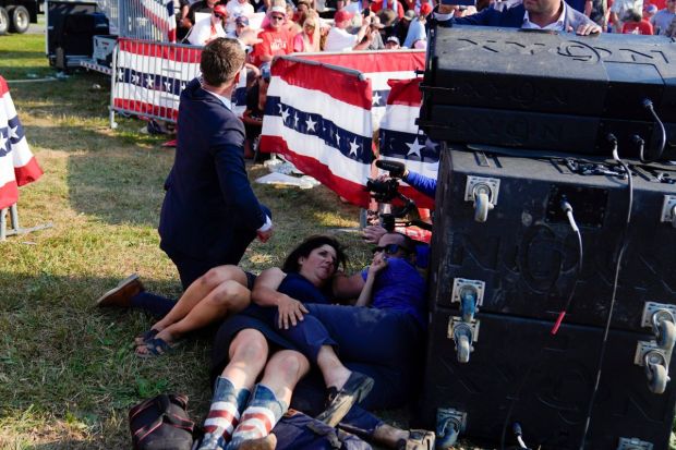 People take cover as U.S. Secret Service agents surround Republican presidential candidate former President Donald Trump on stage(Photo: AP/PTI)