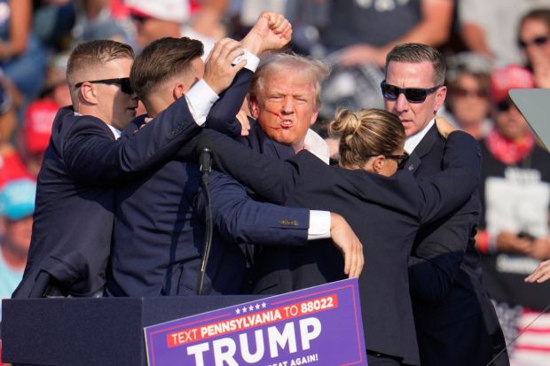 Former President Donald Trump raised his fist to the air while the US Security Agents take him off the stage.(Photo: AP/PTI)