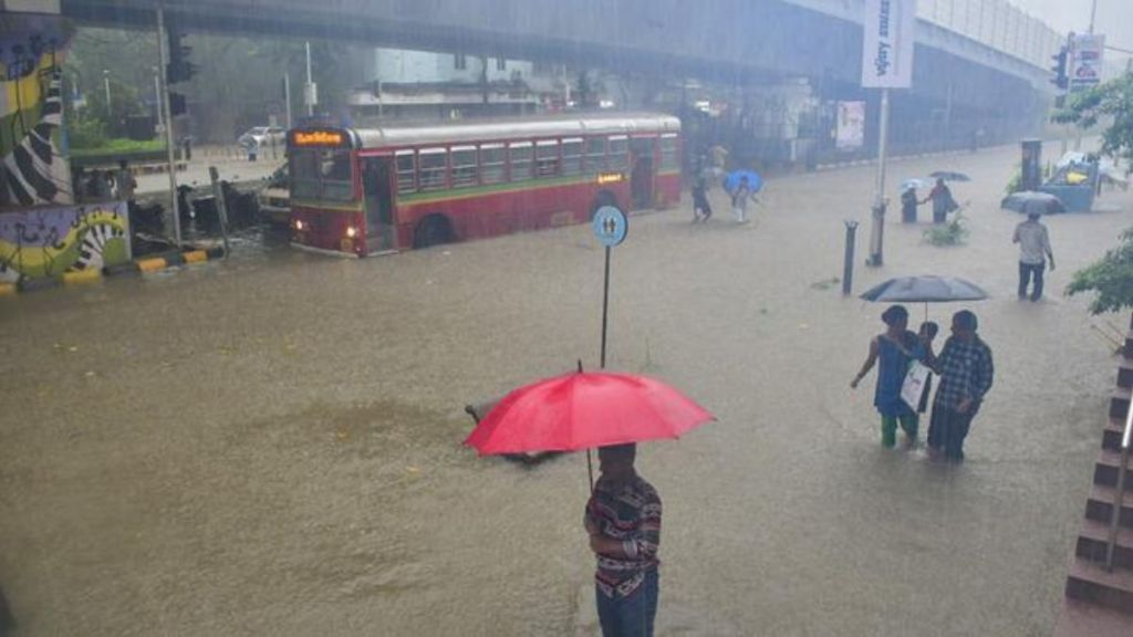 A bus moves on a waterlogged road during monsoon rain