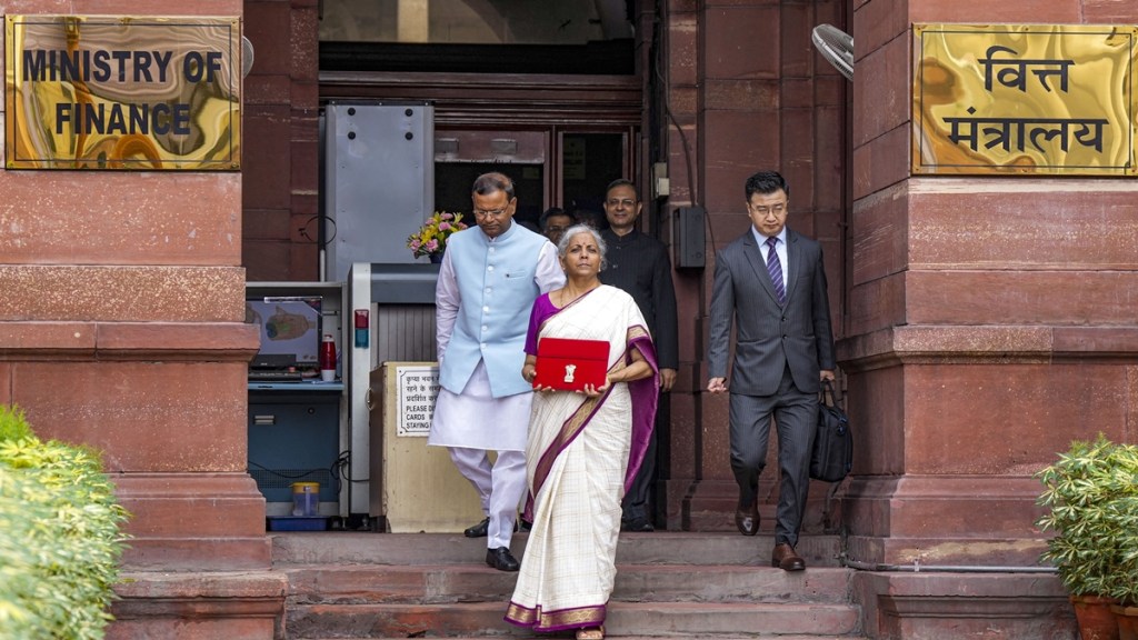 Union Finance Minister Nirmala Sitharaman with a red pouch carrying the Budget documents outside the Finance Ministry in North Block before leaving for the Parliament where she will table the Union Budget 2024-25, in New Delhi, Tuesday, July 23, 2024. Finance MoS Pankaj Chaudhary is also seen. (PTI Photo)
