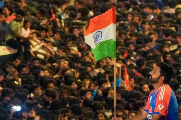 The T20 World Cup-winning Indian cricket team captain Rohit Sharma holds the Indian tricolour during open bus victory parade, in Mumbai. (PTI)