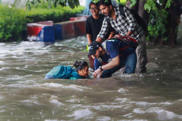 New Delhi: People help a pedestrian who fell on a flooded road after heavy monsoon rains, at ITO. (PTI)