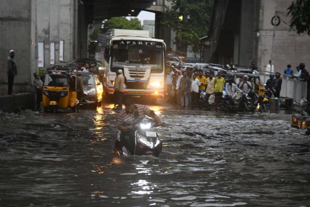 Hyderabad: A man rides a scooter on a flooded road after heavy monsoon rains. (PTI)