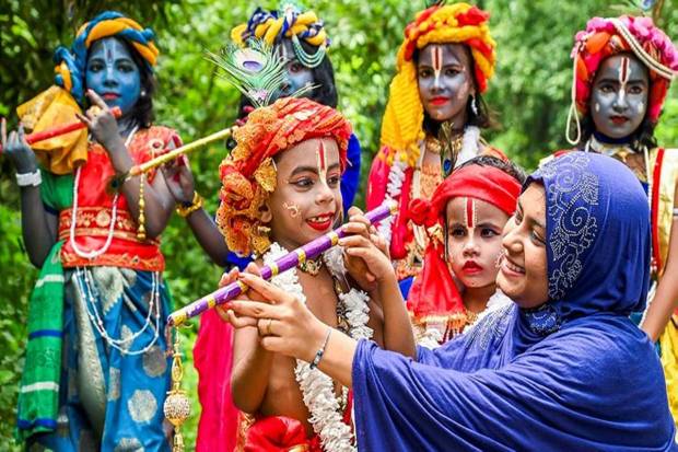 A woman assisting a child dressed as Lord Krishna for a dress competition organised ahead of the festival, in Nadia. (Photo source: PTI)