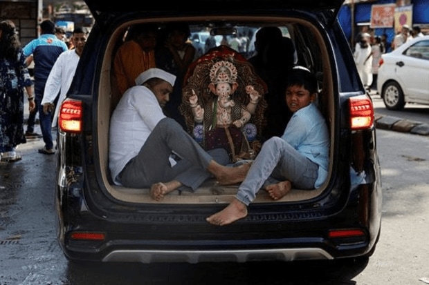 People travel in a car with an idol of the Hindu god Ganesh on the first day of the ten-day long Ganesh Chaturthi festival, in Mumbai. (Photo: Reuters)
