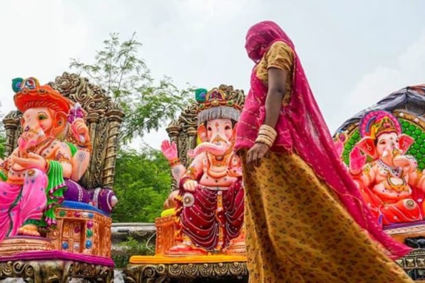 A woman walks past clay idols of Lord Ganesh, being displayed for sale, ahead of Ganesh Chaturthi festival, in New Delhi. (Photo: PTI)