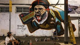 Israeli graffiti artist Maayan, from the Grafitiyul group, rests after she finished working on a graffiti of Hezbollah leader Sayyed Hassan Nasrallah after Israel's military confirmed it had eliminated him in a Beirut airstrike, in Tel Aviv, Israel, September 29, 2024. REUTERS
