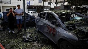 People stand near a damaged car at a site of houses damaged following a rocket attack from Lebanon, amid cross-border hostilities between Hezbollah and Israel, in Kiryat Bialik, Israel. (Photo: Reuters)