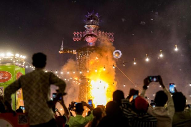 People watch an effigy of demon king 'Ravana' burns during Vijayadashami festival celebration organised by the Lavkush Ramlila Committee, at the Ramlila ground in Delhi.