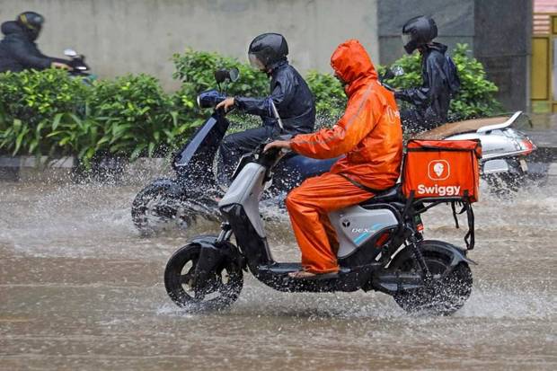 Delivery boys move through waterlogged roads amid heavy rains in Bengaluru. (Photo source: PTI)